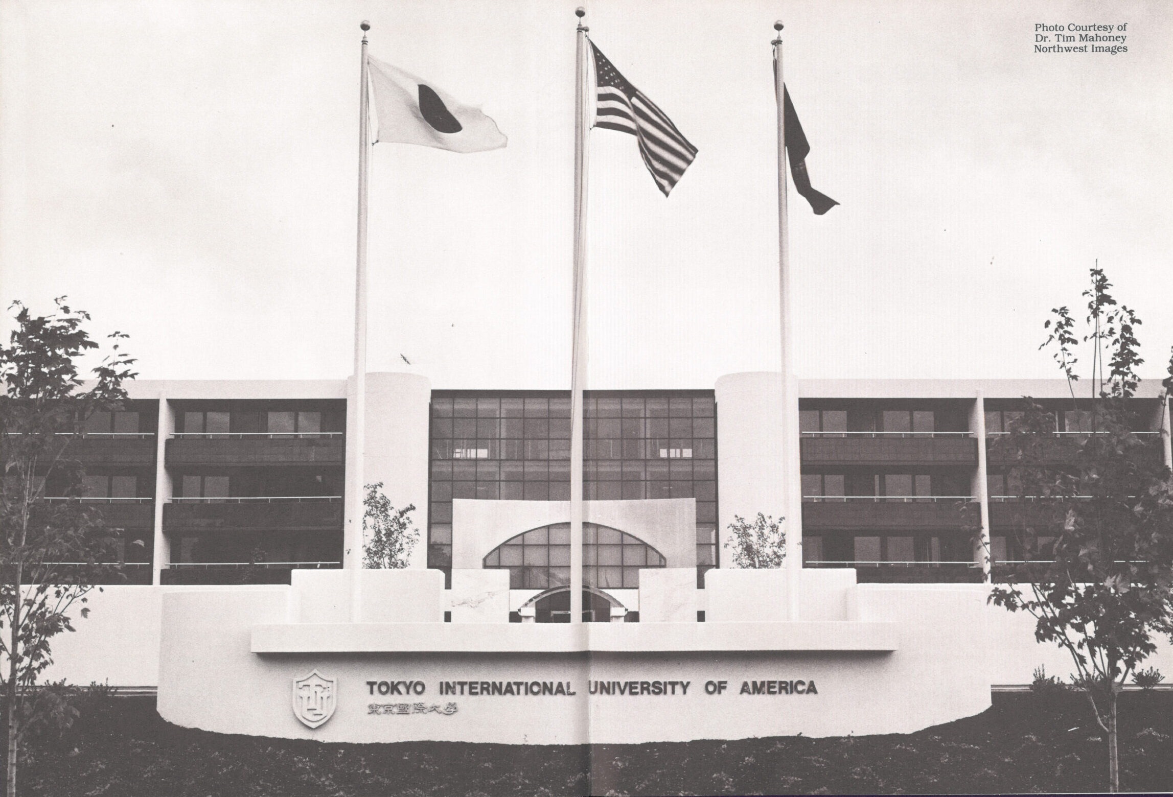 A Japanese, American and Oregon flag wave on the outside of the Tokyo International University of America.